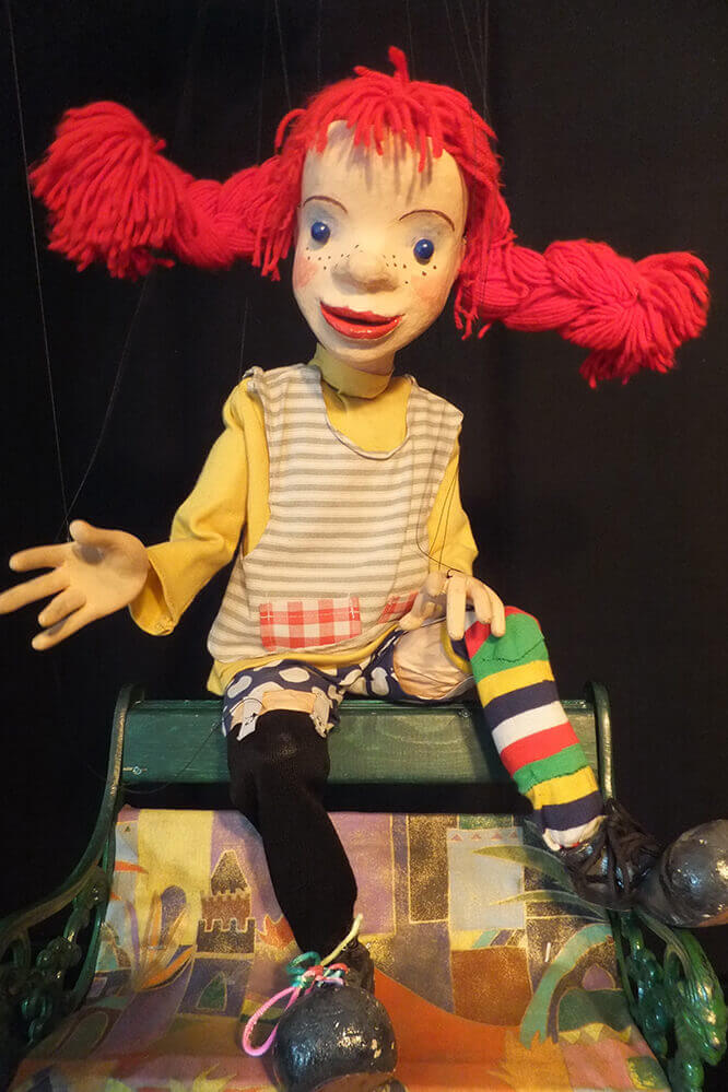 Foto: Pippi Langstrumpf (Marionette) sitzt auf der Rückenlehne einer Bank