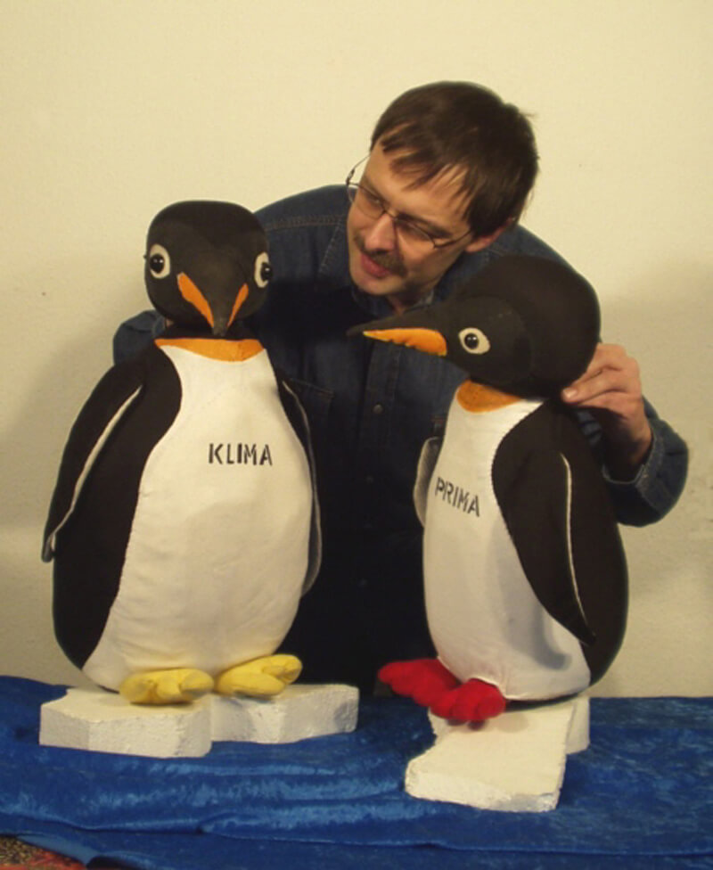 Foto: Die beiden Pinguine Klima und Prima jeweils auf einer kleinen Eisscholle. In der Mitte Puppenspieler Wolfgang Kaup-Wellfonder