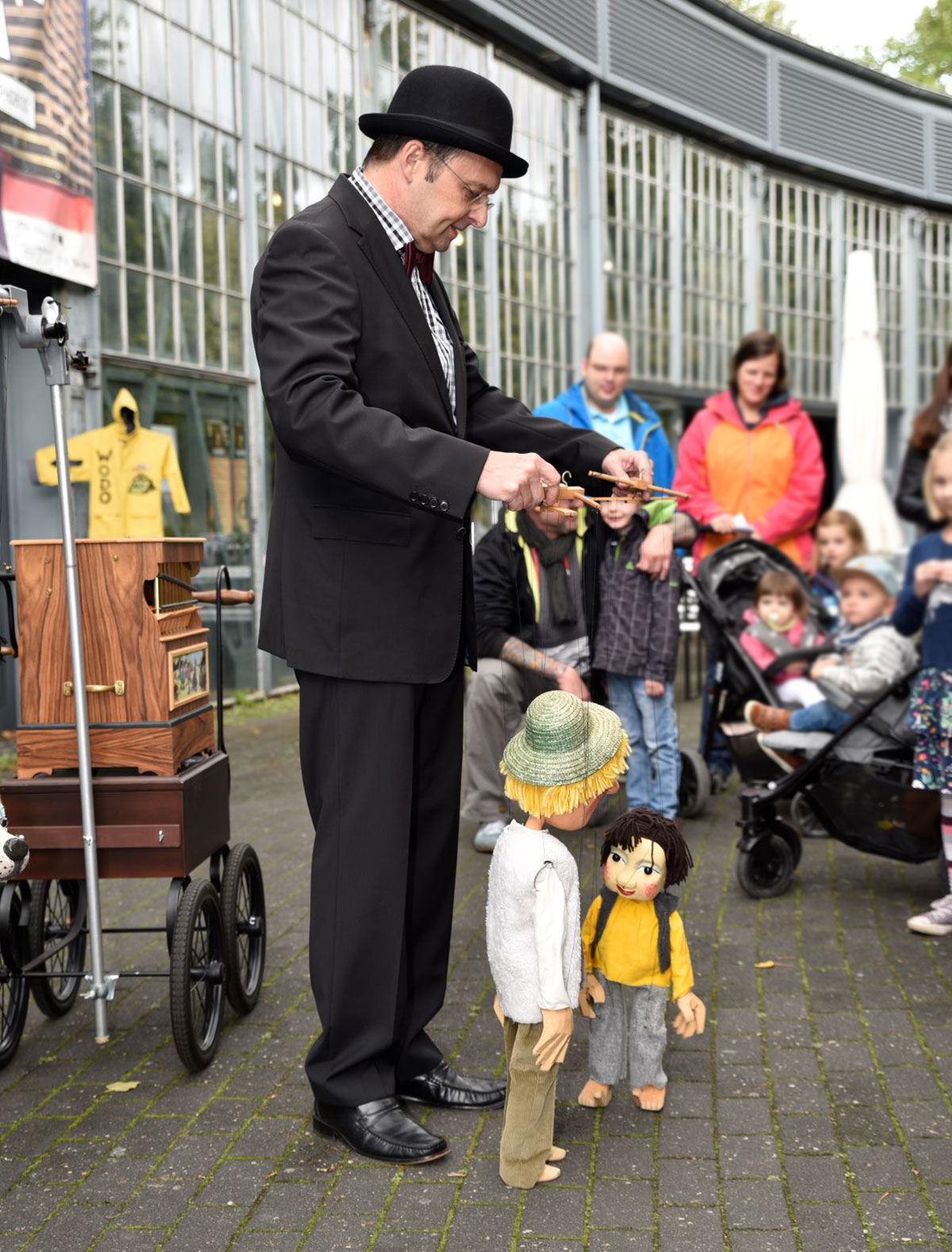 Foto: Wolfgang Kaup-Wellfonder mit zwei Marionetten und der Drehorgel vor dem Ringlokschuppen. 